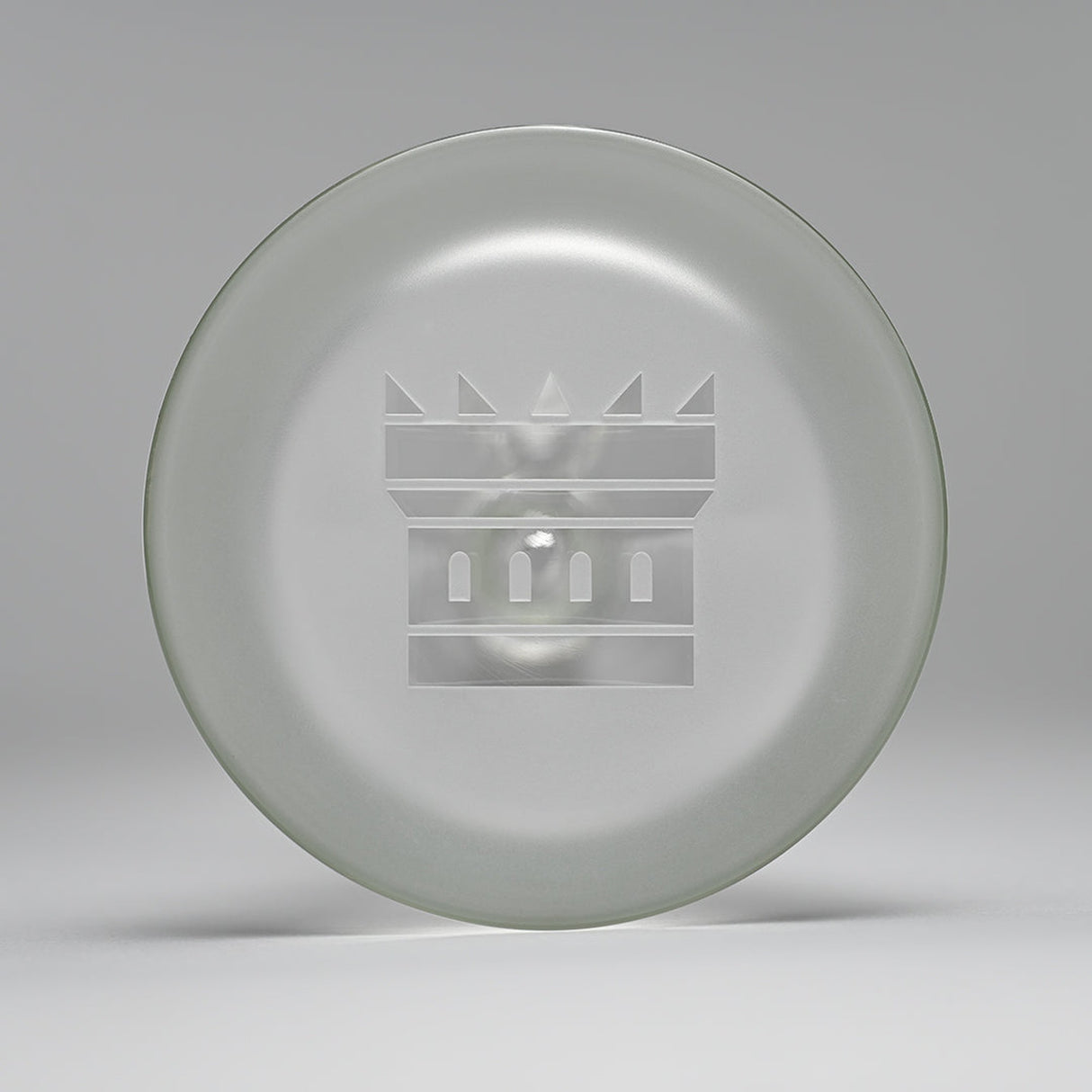 18 Glass Beaker Bong - Lines: A glass plate with a crown logo, showcasing intricate etched patterns, crafted for stability and elegance in high-quality borosilicate glass.