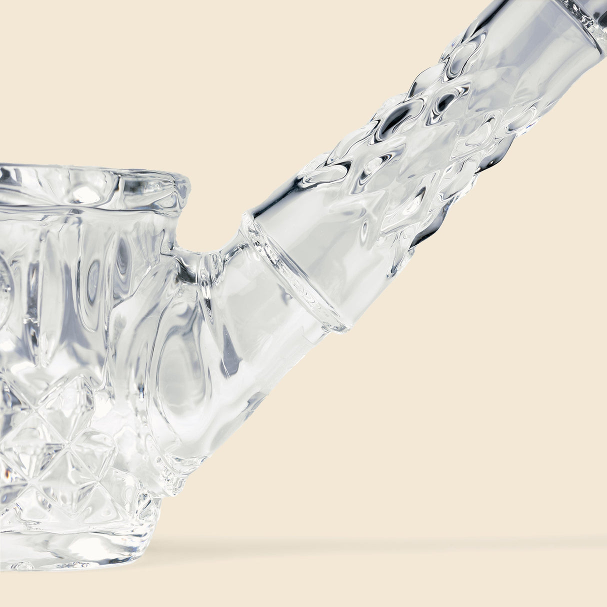 Close-up of the NWTN Home Highball Pipe, showcasing its intricate diamond and wedge-cut patterned borosilicate glass, with a bowl on the left and angled mouthpiece on the right.