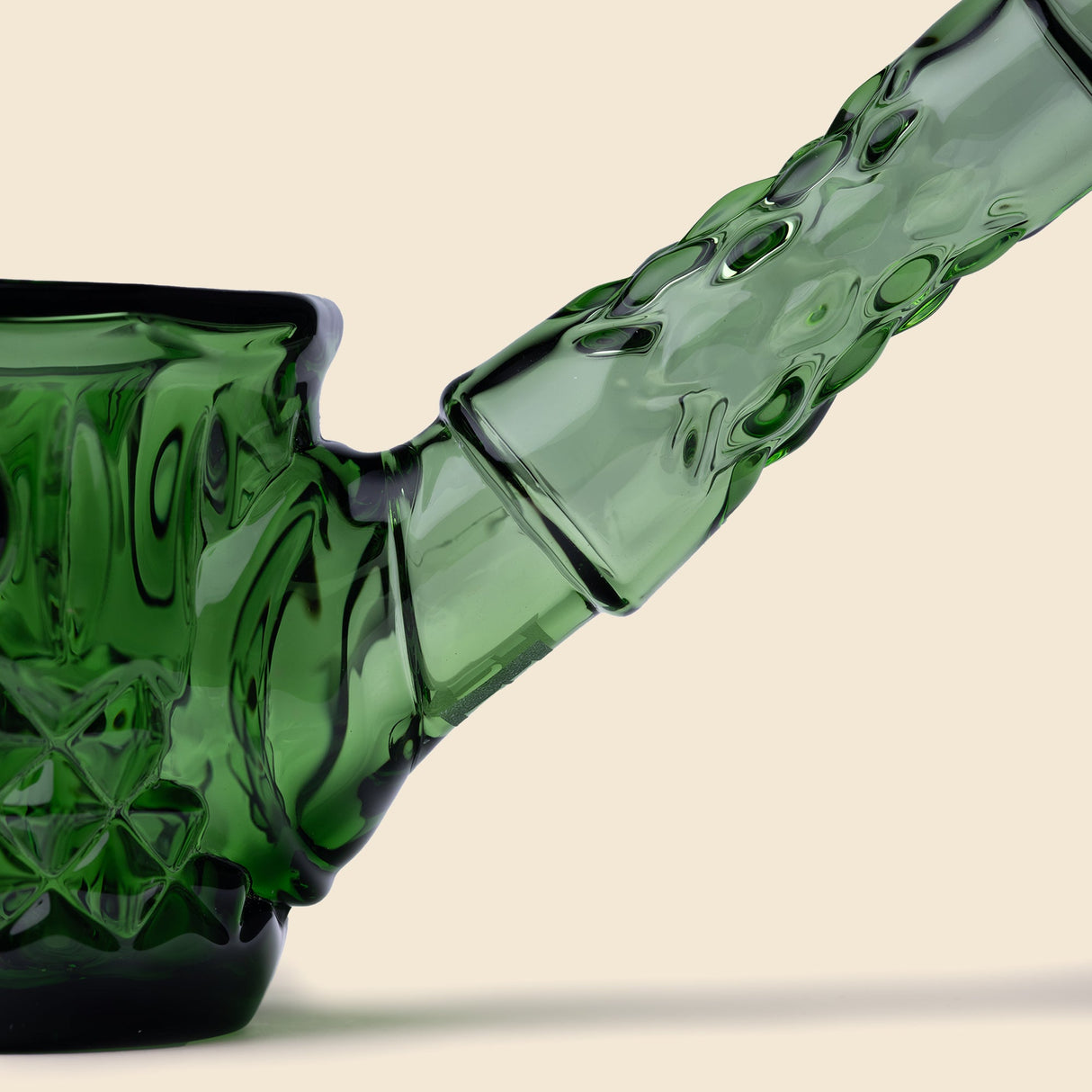 Close-up of the Highball Pipe's green-tinted glass bowl and downstem joint, showcasing its intricate diamond and wedge-cut detailing against a plain background.