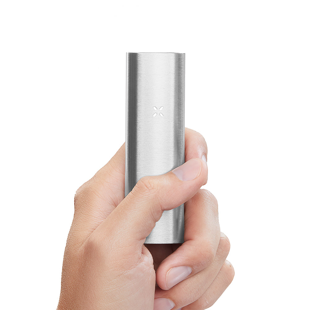 Hand holding a PAX 2 Dry Herb Vaporizer, a slim, pen-style device with sleek design, illustrating its portability and ergonomic features against a white background.