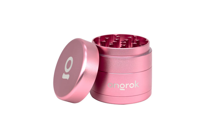 Mini EZ Grinder - 55mm, pink cylindrical design, open to show triangular metal teeth, showcasing its compact, durable build and smart storage features.