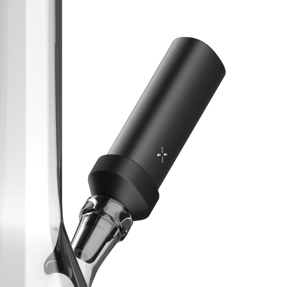 PAX FLOW Bong Adapter 2 - Black, a matte-black cylindrical module with a cross-shaped LED, attaches magnetically to a clear glass joint for smooth, cool vapor sessions.
