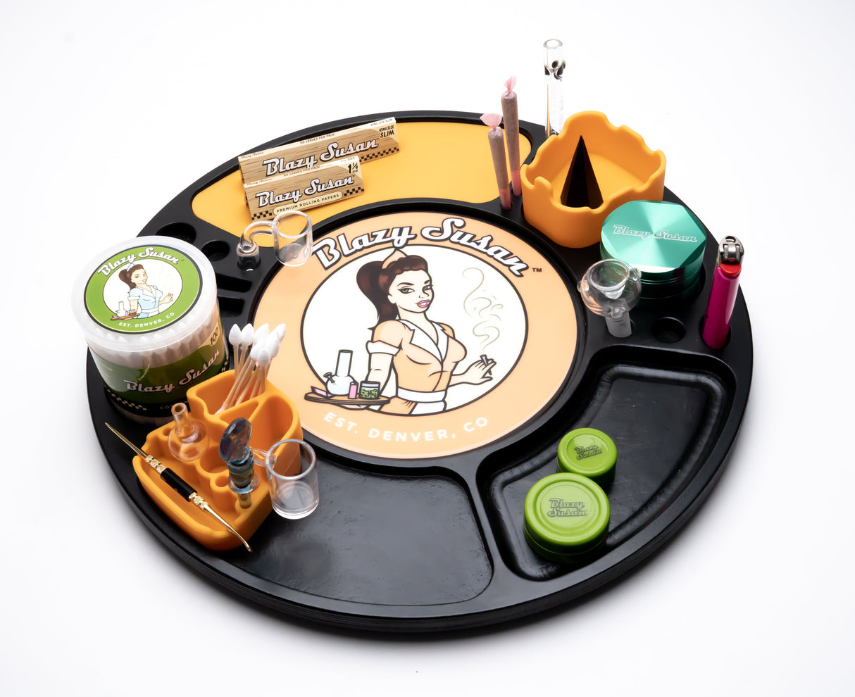 Blazy Susan Spinning Rolling Tray showcasing organized tools, grinders, papers, and accessories on a black circular platform with a central Blazy Susan logo.