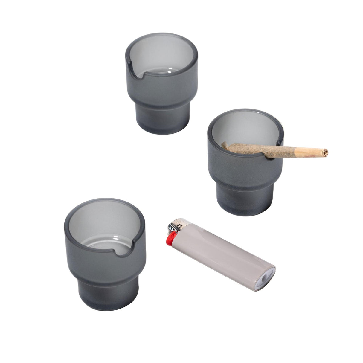 Flower Pots Ashtray Set: Three gray cylindrical mini-ashtrays with a rolled joint in one, crafted from borosilicate glass with sandblasted exterior and functional grooves.