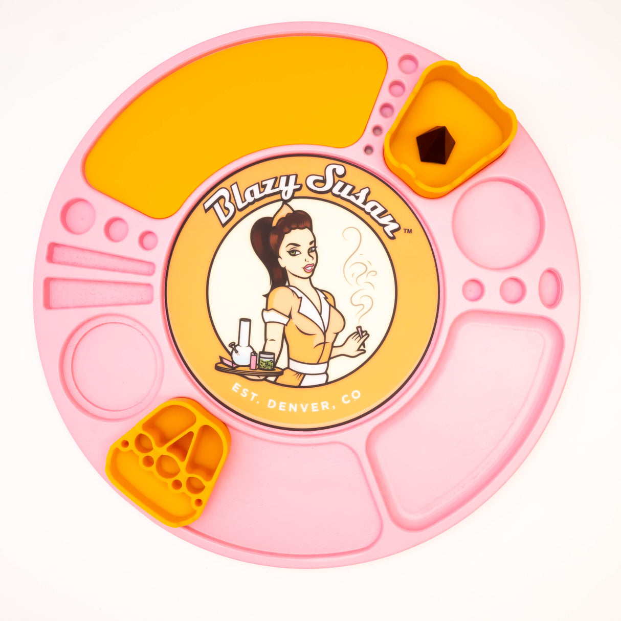 Round pink silicone Spinning Rolling Tray with recessed compartments, featuring yellow insert trays; central Blazy Susan branding with waitress-logo. Includes a small pyramid-shaped object.