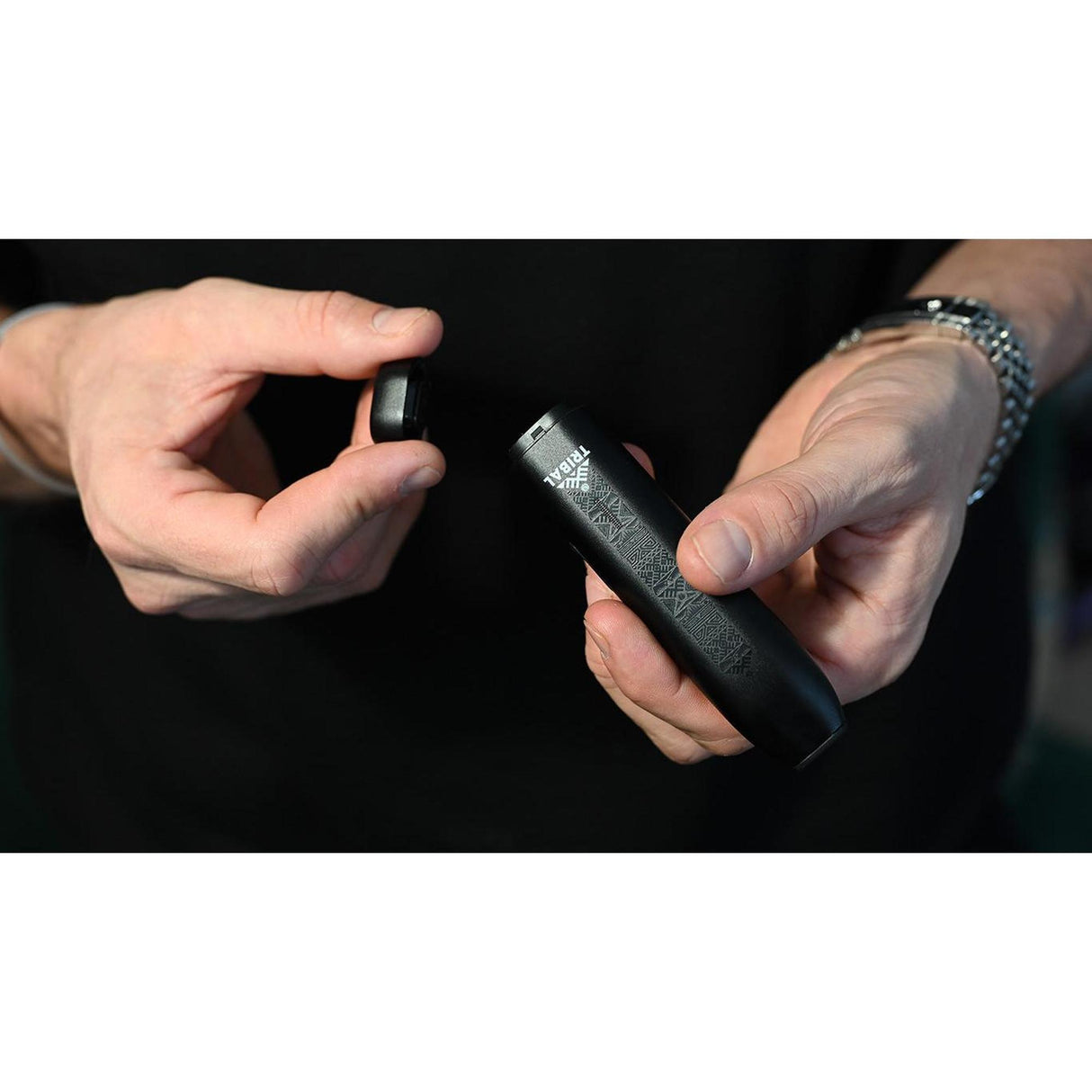 Hand holding the TRIBAL AEROLITH Dry Flower Vaporizer, a sleek black cylindrical device designed for portability and efficient, combustion-free vaporization.