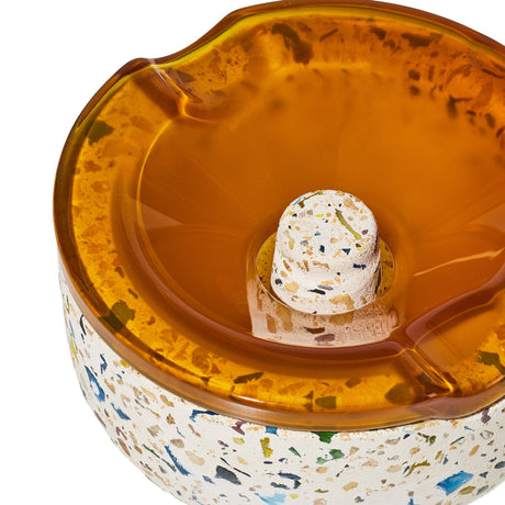 Symi Ashtray with terrazzo base and amber-tinted borosilicate glass top featuring grooves for cigarettes; a stylish, functional tabletop accessory.