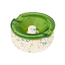 Symi Ashtray with a terrazzo concrete base and removable translucent green borosilicate glass top featuring cigarette grooves and a central raised knob.