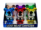 Countertop display box showcasing Grinder - Lost Bunny, featuring six metallic, cartoon-style bear herb grinders with chrome finishes, highlighting their compact, durable, and polished design.