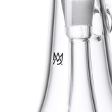 Close-up of the Lumina - Clear, a borosilicate glass bubbler with a cylindrical chamber, frosted joint, and stylized “M” logo, featuring a 4-slot percolator.