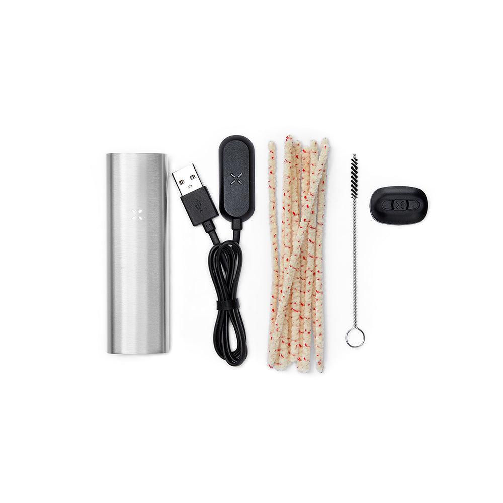 PAX 2 Dry Herb Vaporizer kit with brushed-metal body, USB charger, pipe-cleaners, twisted-wire brush, and oven-lid tool, showcasing its portable, sleek design.