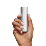 Hand holding PAX 2 Dry Herb Vaporizer, slim and silver with rounded edges, showcasing the four-petal “X” logo, highlighting its compact, sleek design.