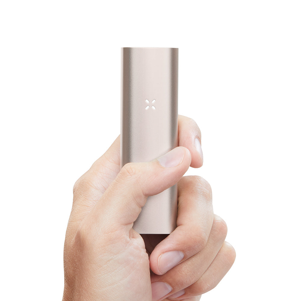 Hand holding PAX 3 Basic Kit, a compact, pill-shaped vaporizer with metallic finish and X-pattern LED, showcasing its sleek design and portable size.