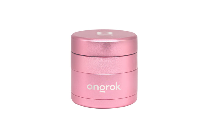 Mini EZ Grinder - 55mm: Compact cylindrical metallic pink grinder with a stylized O on the lid, featuring deep chambers and a magnetic locking system.