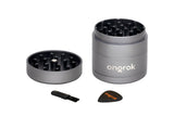 Mini EZ Grinder - 55mm: Disassembled 4-piece metal grinder with pyramid teeth, magnetic lid, and two accessories—a cleaning brush and scraper—for efficient herb processing.