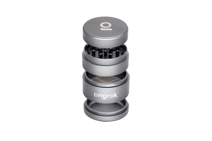 Mini EZ Grinder - 55mm, shown exploded: magnetic lid, grinding chamber with teeth, mesh-screen section, and catch-cup, highlighting its compact, functional design.