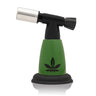 5 Blow Torch Turbo Flame with green body, black top, cannabis-leaf logo. Compact, ergonomic design ideal for precision tasks, offering a powerful 2500°F flame.