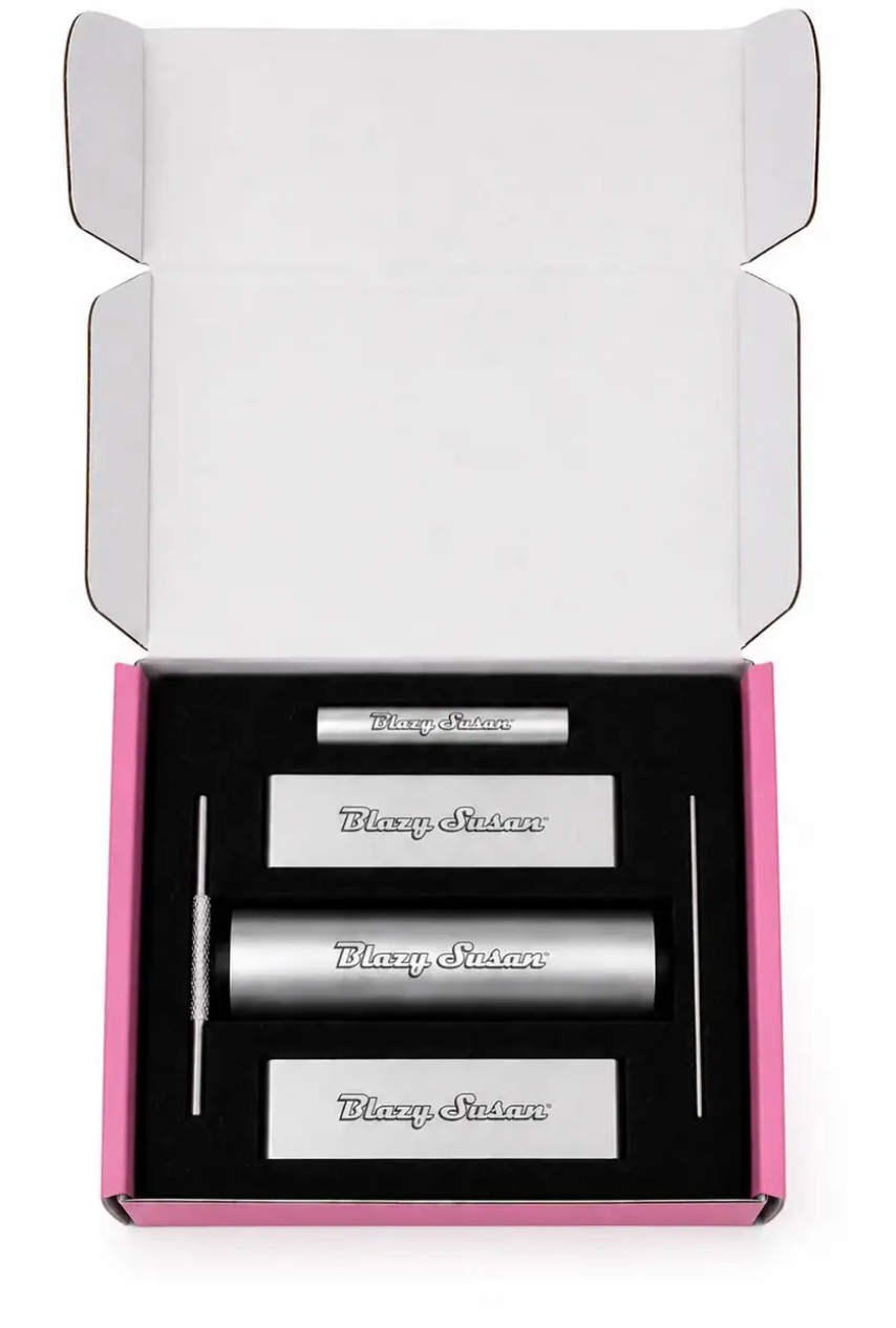 blazy susan rolling kit displayed inside an open pink and black box, featuring a cylindrical rolling accessory, two rectangular pieces, and a metal tool