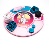 Blazy Susan pink spinning rolling tray with compartments, holding branded rolling papers, herb grinder, silicone holders, lighter, dab tool, stash jars, and cotton swabs.