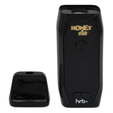 HoneyStick HRB+ Dry Herb Vaporizer in black with gold branding, detachable mouthpiece cap, LED display, and USB C port visible.