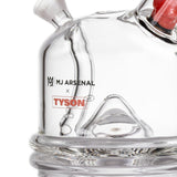Close-up of MJA x Tyson 2.0 Punch-Out Bubbler, showcasing its clear glass, rounded base, joint for attachments, and printed logos. Compact, durable design for smooth, powerful sessions.