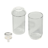Vesper Gravity Bong: Three clear cylindrical glass pieces, including an open-top jar, a domed-lid cylinder, and a matching cap, showcasing elegant, gravity-powered design.