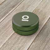 Aluminum Storage Puck on a wooden surface, featuring a round design with an airtight seal, ideal for discreet, pocket-sized storage of small items.