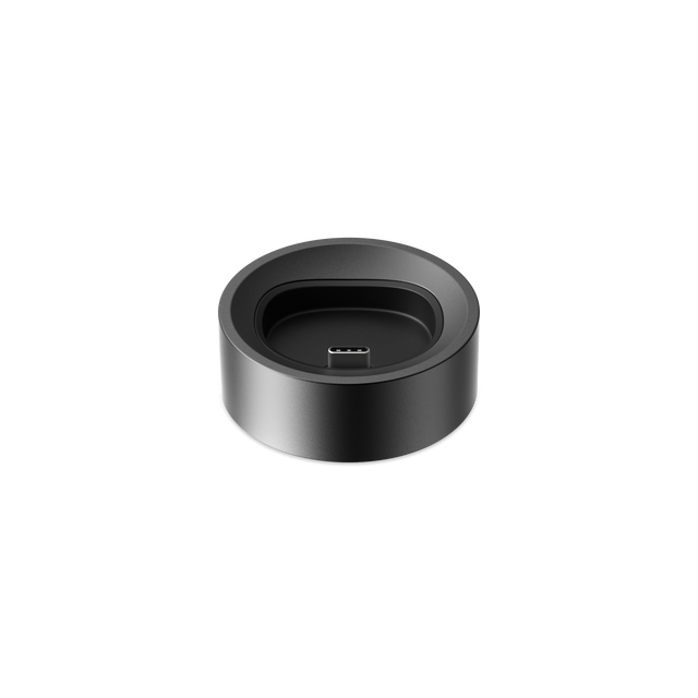 PAX FLOW Charging Dock: A sleek, matte black circular dock with USB-C plug, designed for efficient charging and organization of the PAX FLOW device.