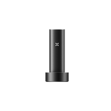 PAX FLOW vaporizer in matte-black, cylindrical design, resting in a round dock, featuring an illuminated “X” logo, highlighting its sleek, portable build.
