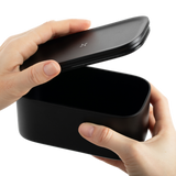 Hand holding a black Stash Jar, designed for smell-proof storage of herbs, featuring a sleek, portable design made from high-quality aluminum.