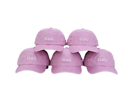 Five pink Slou roller caps arranged together, each featuring a curved brim and white Slou logo embroidered on the front
