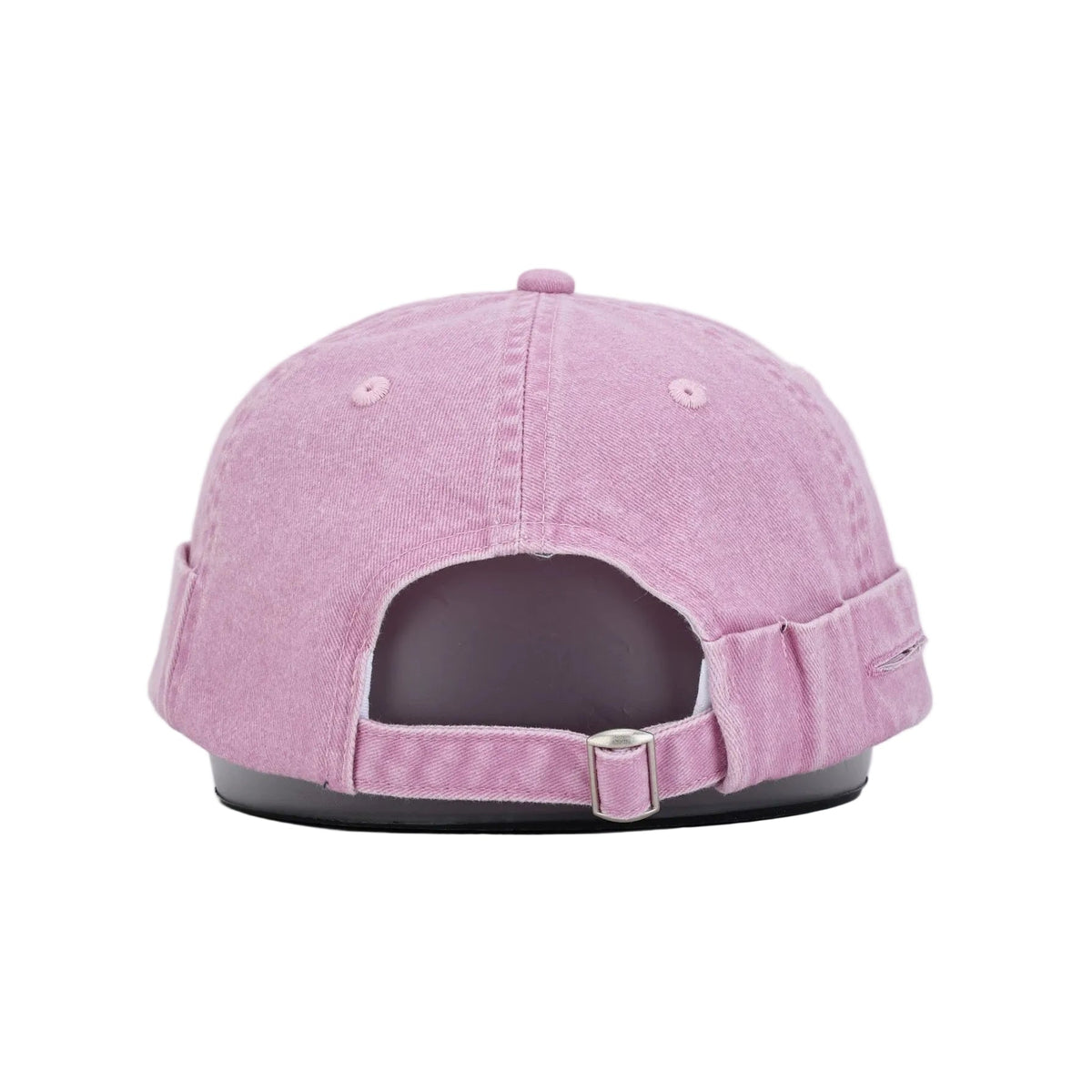 A light pink washed cotton rollers cap shown from the back, featuring an adjustable strap and a silver metal buckle, displayed on a black stand