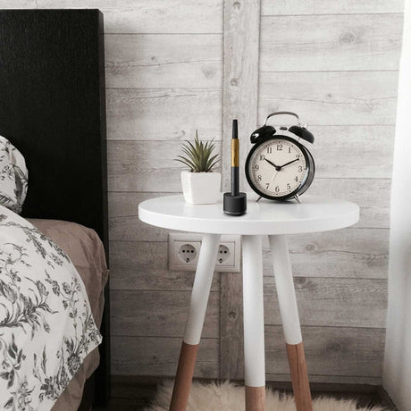 Base Charger - Black on a white table, holding a slim black device. Accompanied by a potted succulent and a twin-bell alarm clock at 10:10.