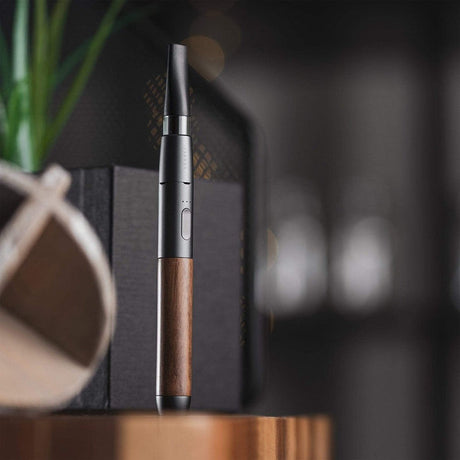 Craftsman 510 Thread Battery - Slate/Walnut: A slim, pen-style vaporizer with a metal and wood-grain body, single button, tapered mouthpiece, on a tabletop.
