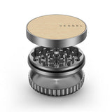 Vessel Mill Grinder, a 3-piece metal accessory with a wooden top, features a grinding section and catch-cup, ideal for precise herb preparation.