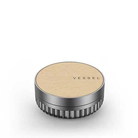 Vessel Mill Grinder: A round, aluminum jar with ribbed sides and a wooden top, engraved VESSEL, used for precise dry herb grinding.