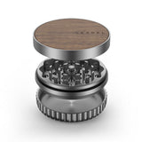 Vessel Mill Grinder with wood-veneer lid, visible grinding teeth, and catch chamber, showcasing its precision-engineered, three-piece aluminum design for dispensaries and headshops.