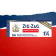 1 1/4 White Rolling Paper & Tips box featuring Zig-Zag logo, highlighting premium quality, natural gum Arabic seal, and included tips for enhanced smoking experience.